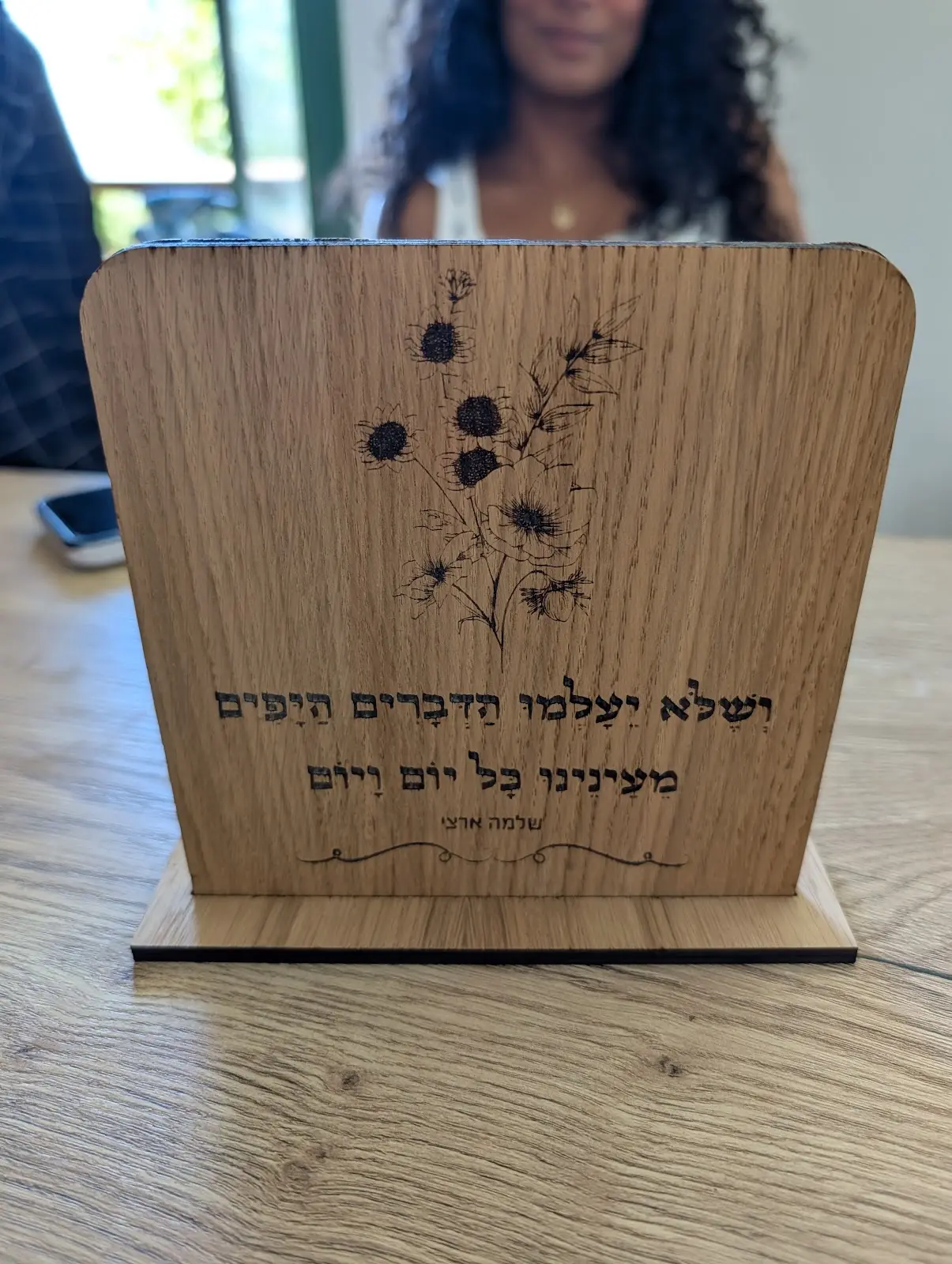 מעמד עץ עם פרחים וכיתוב